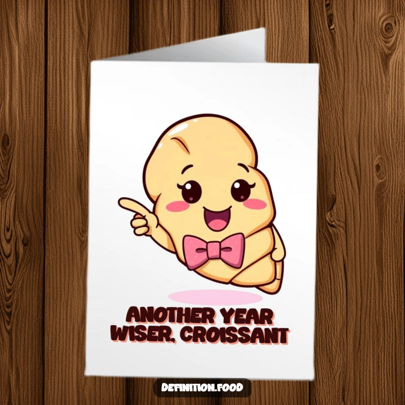 Funny Free Printable Birthday Card: Cheerful croissant in a bow tie pointing humorously at a colorful definition, ready to celebrate.